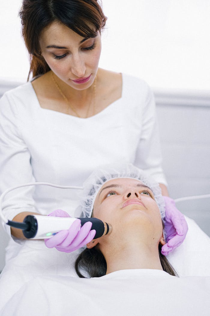 A Woman Lying in the Clinic Bed while having Facial Treatment