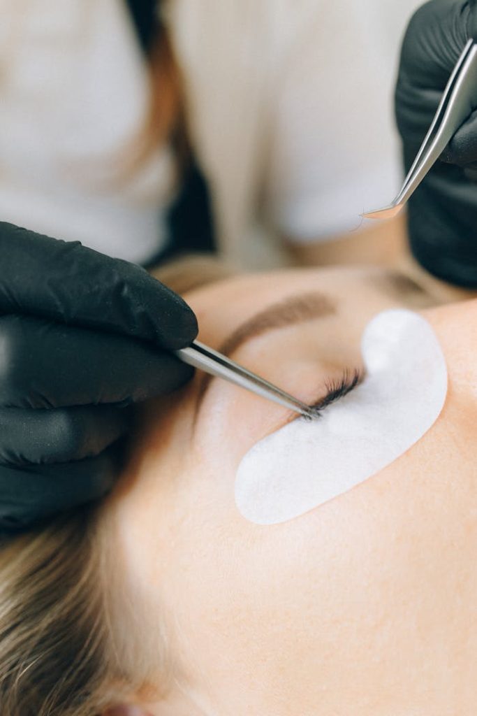 Hands Putting Cosmetic Eyelashes on Clients Eye